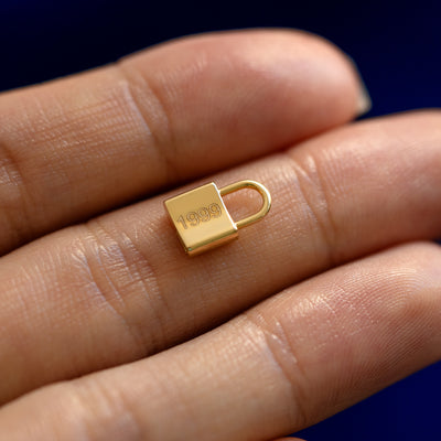 A solid gold lock charm with 1999 engraved on it