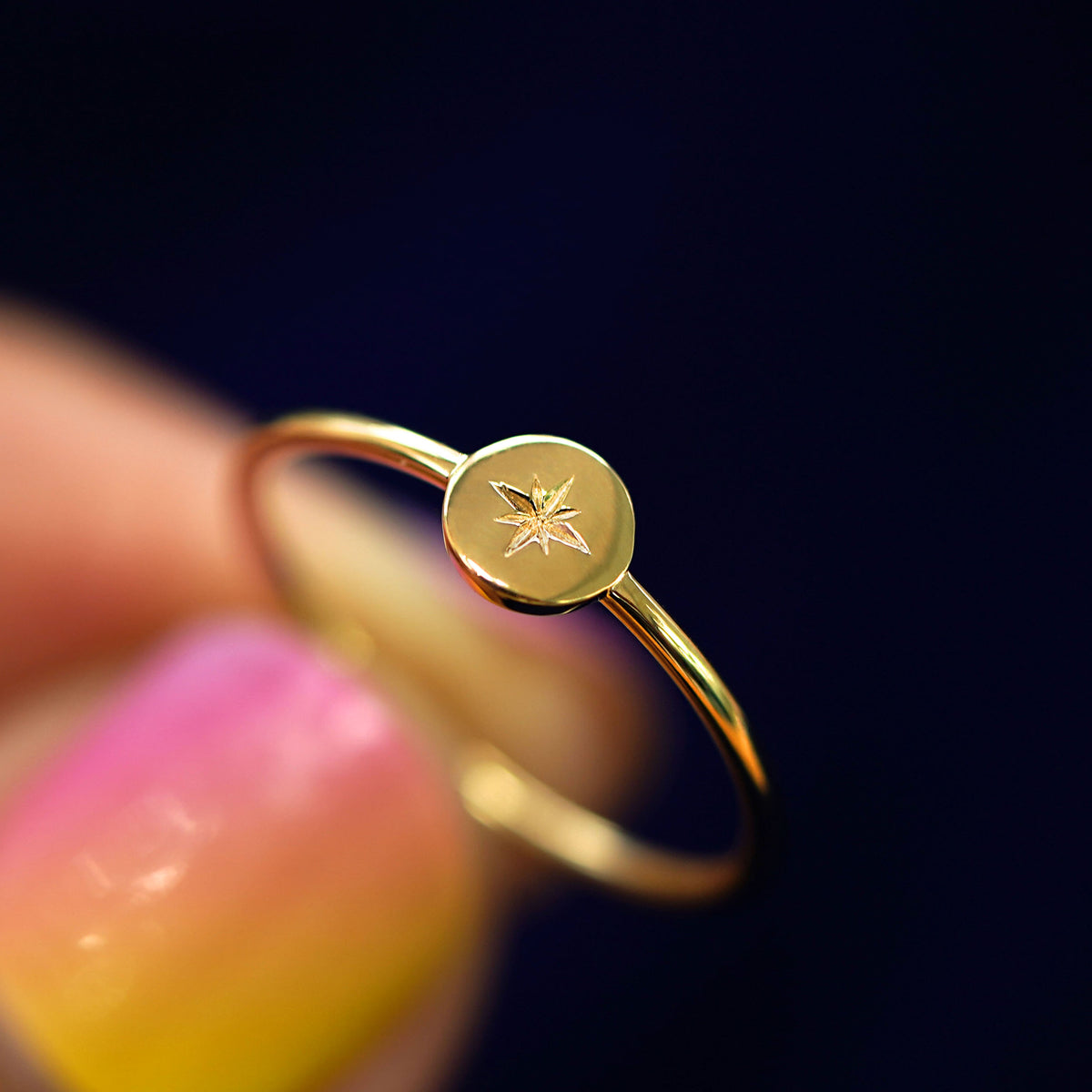 A model holding a 14k yellow gold star disk ring between their fingers