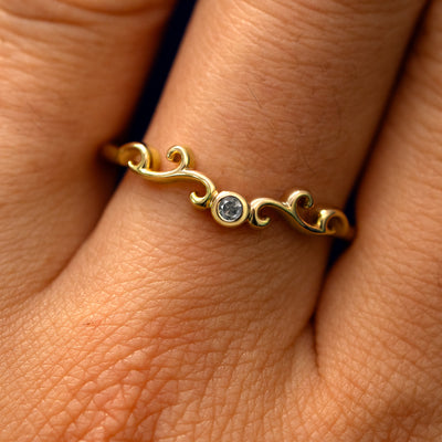 Close up view of a model's fingers wearing a 14k yellow gold Open Filigree Chevron Diamond Band