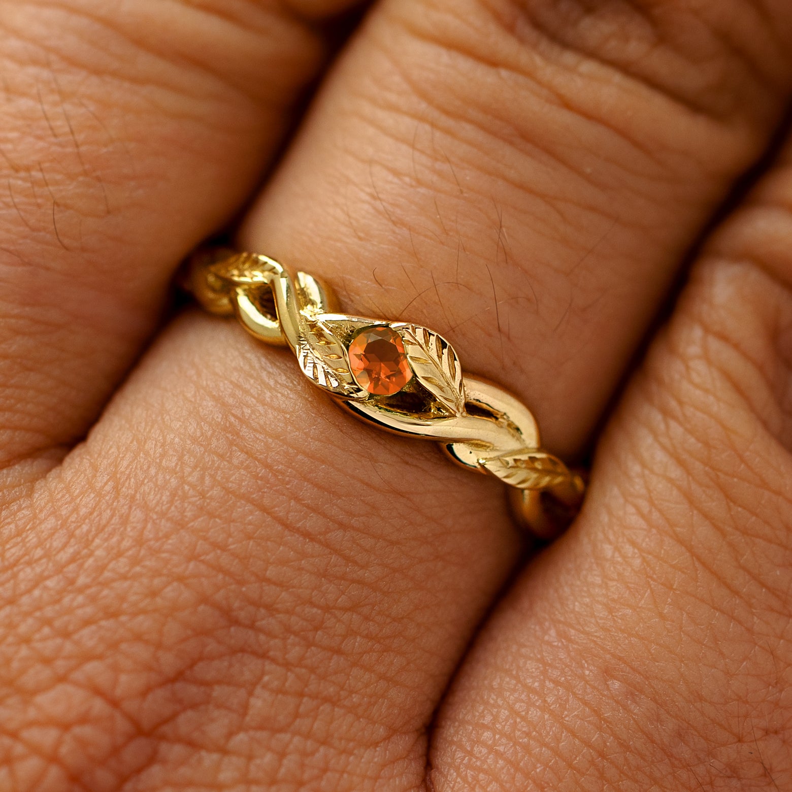 A solid 14k yellow gold fire opal  leaves and vines ring on a model's finger