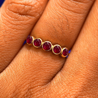 Close up view of a model's hand wearing a yellow gold 5 Gemstones Ring in ruby