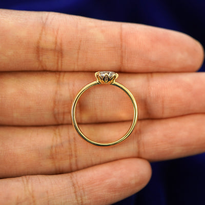 A yellow gold Diamond Petal Ring in a model's hand showing the thickness of the band