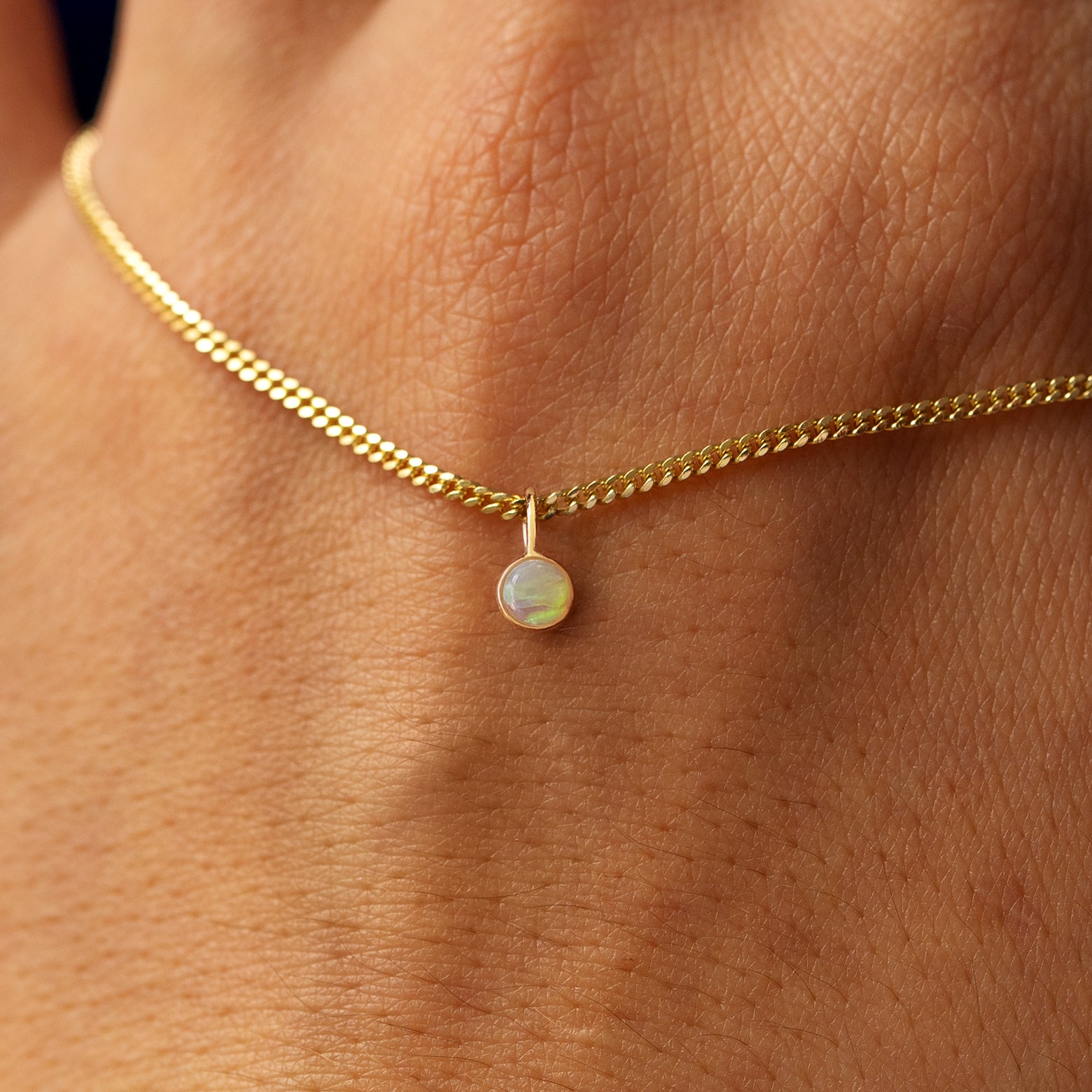 Close up view of a 14k yellow gold Gemstone Necklace on Mini Miami Chain draped across the back of a model's hand