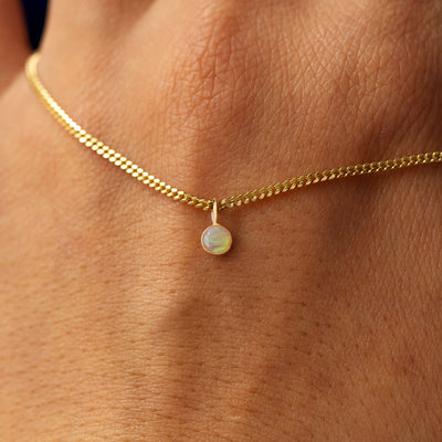 Close up view of a 14k yellow gold Gemstone Necklace on Mini Miami Chain draped across the back of a model's hand