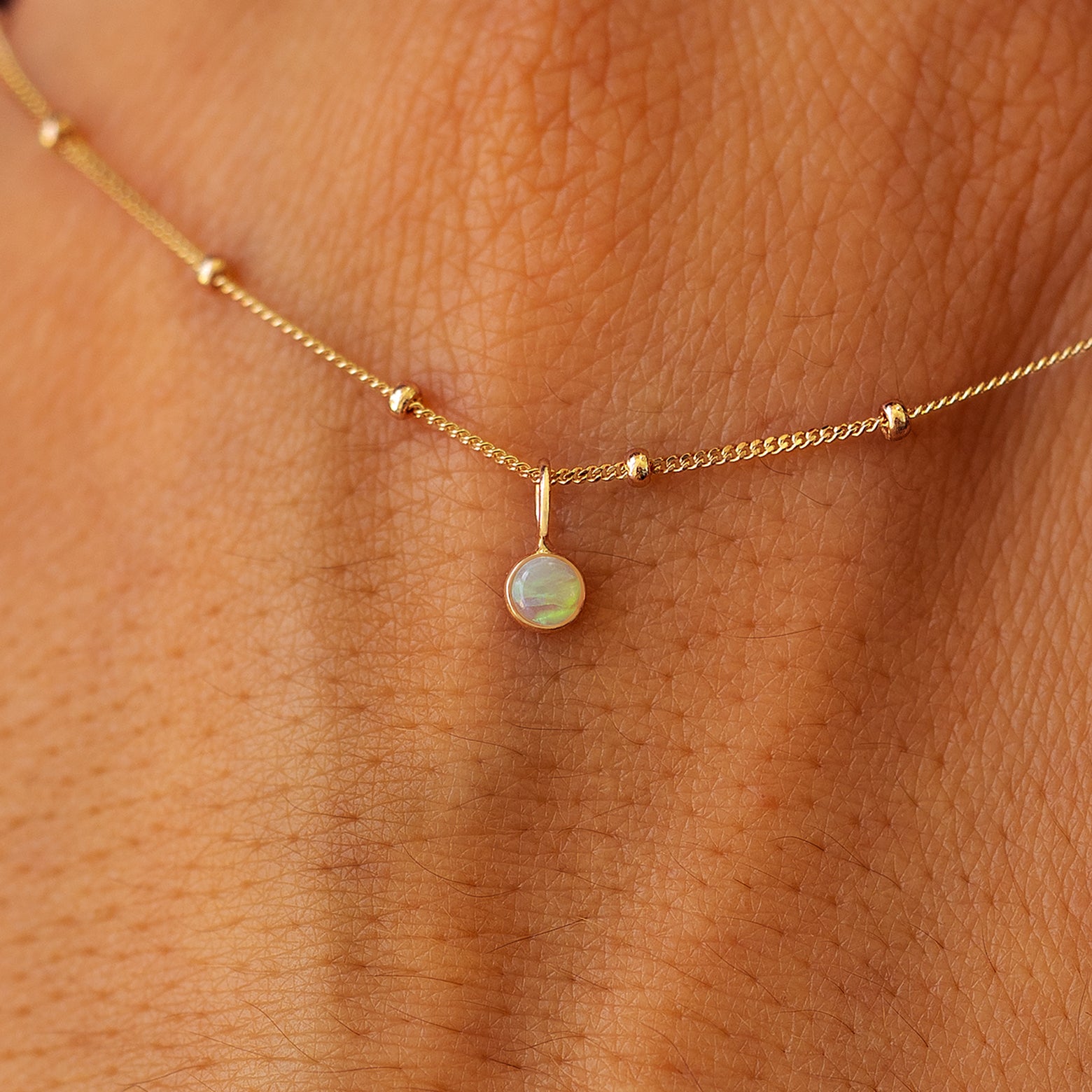 Close up view of a 14k yellow gold Gemstone Necklace on Beaded Essential Chain draped across the back of a model's hand