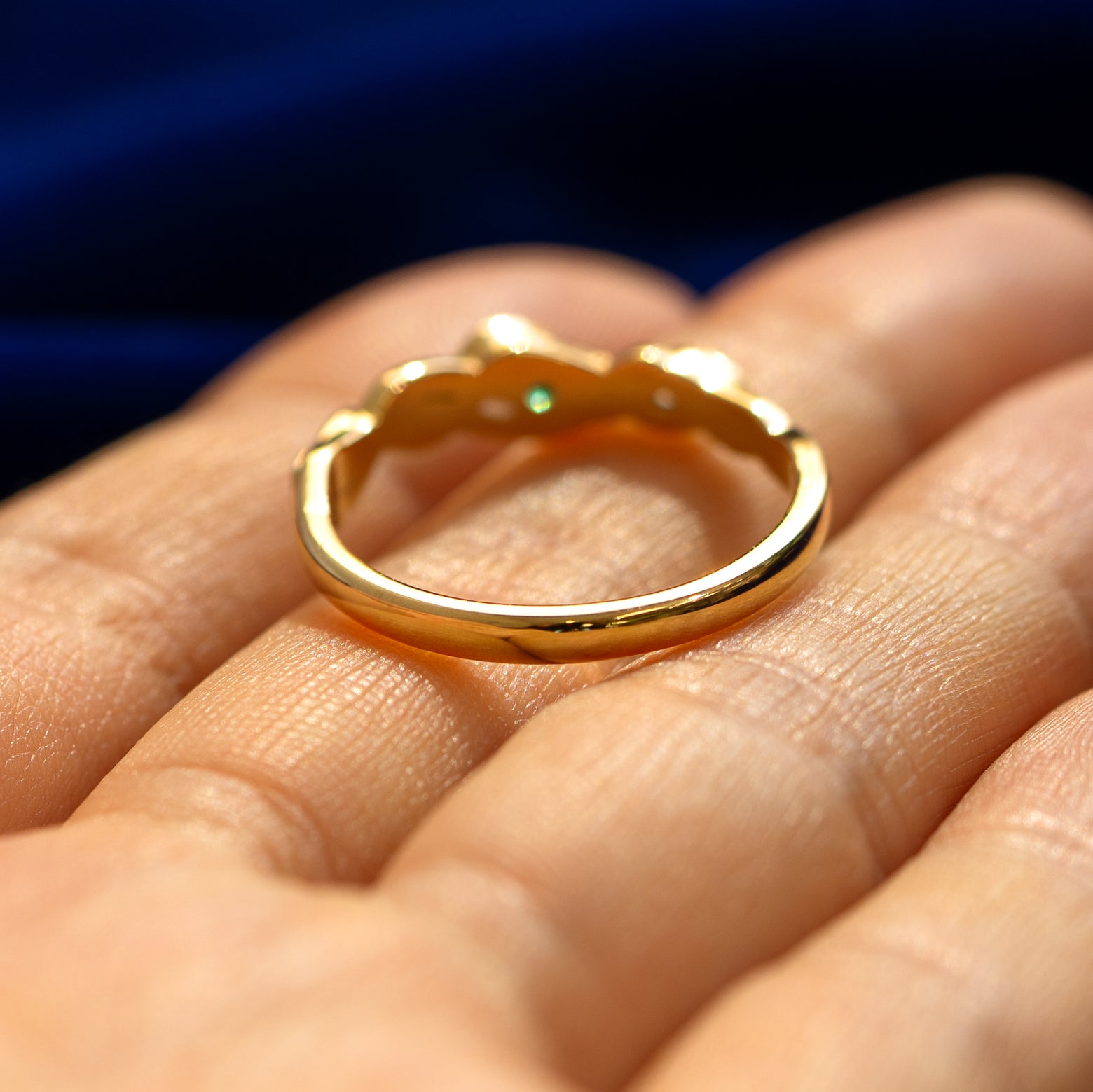 A yellow gold Gemstone Leaves and Vines Ring in a model's hand showing where the braid ends and the smooth band begins