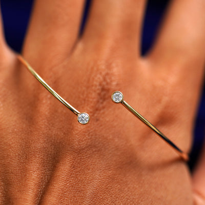 A solid gold clear diamond Gemstone Bypass Bangle  shown on the back of a model's hand