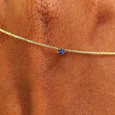 Close up view of a 14k yellow gold Gemstone Cable Necklace draped across the back of a model's hand