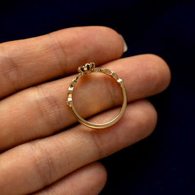 A yellow gold Black Moissanite Leaf Ring in a model's hand showing the thickness of the band