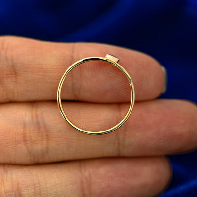 A gemstone monogram ring laying flat in a models hand to show the thickness of  the band