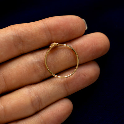A yellow gold Pink Sapphire Gemstone Flower Ring in a model's hand showing the thickness of the band