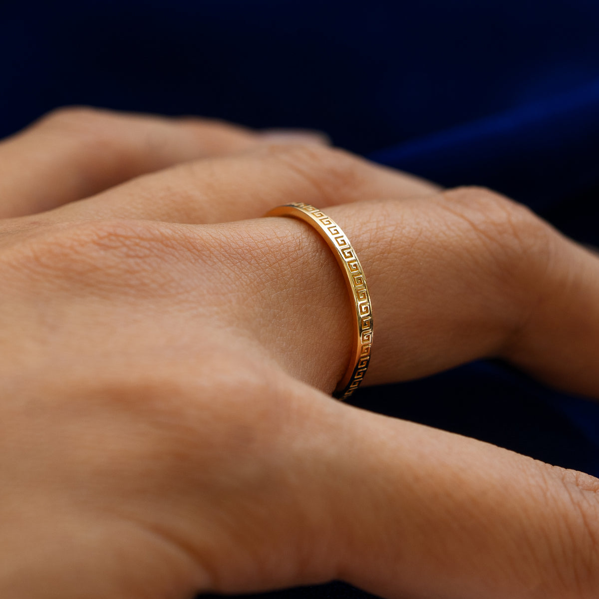 Side view of a model wearing a solid 14k yellow gold geometric grass band to show the raised engraving