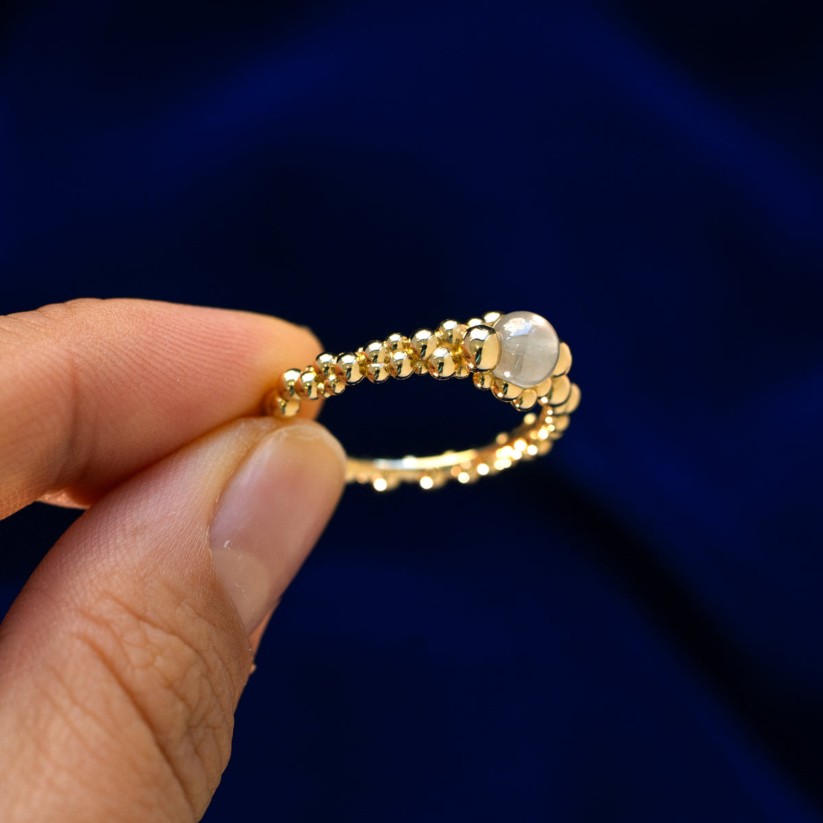 A model holding a diamond bubble fidget ring between two fingers to show how the bead looks from the side