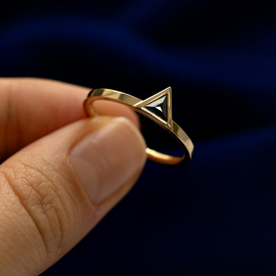 A triangle diamond ring titled sideways to see the details of the stone cut and bezel setting