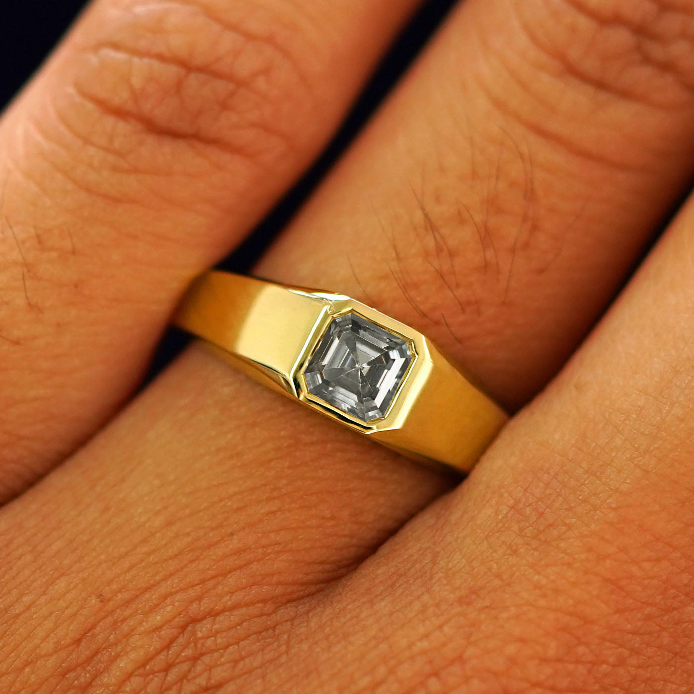 Close up view of a model's fingers wearing a yellow gold lab gray moissanite Asscher Gemstone Signet Ring