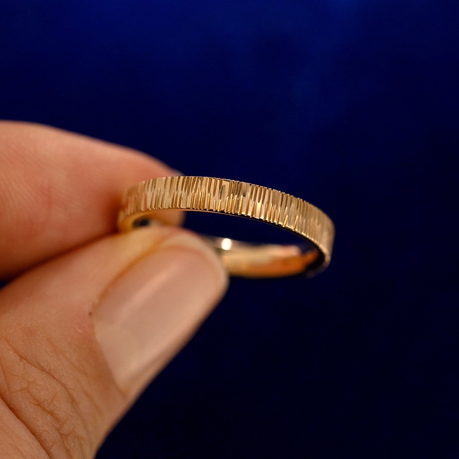 A model holding a Baguette Green Sapphire Wood Band up to show the details of the design and the inside of the ring