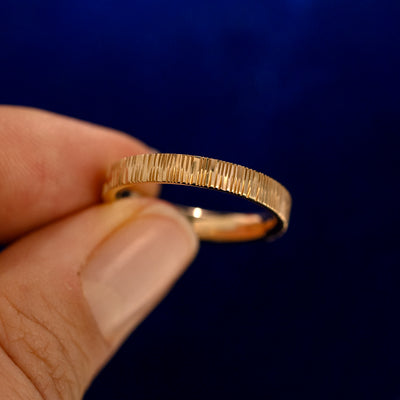 A model holding a Baguette Green Sapphire Wood Band up to show the details of the design and the inside of the ring