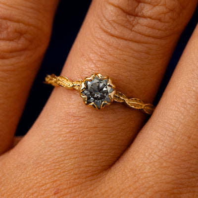 A solid 14k yellow gold Grey Moissanite Leaf Ring on a model's finger