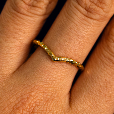 Close up view of a model's fingers wearing a 14k yellow gold hammered finish Chevron Band