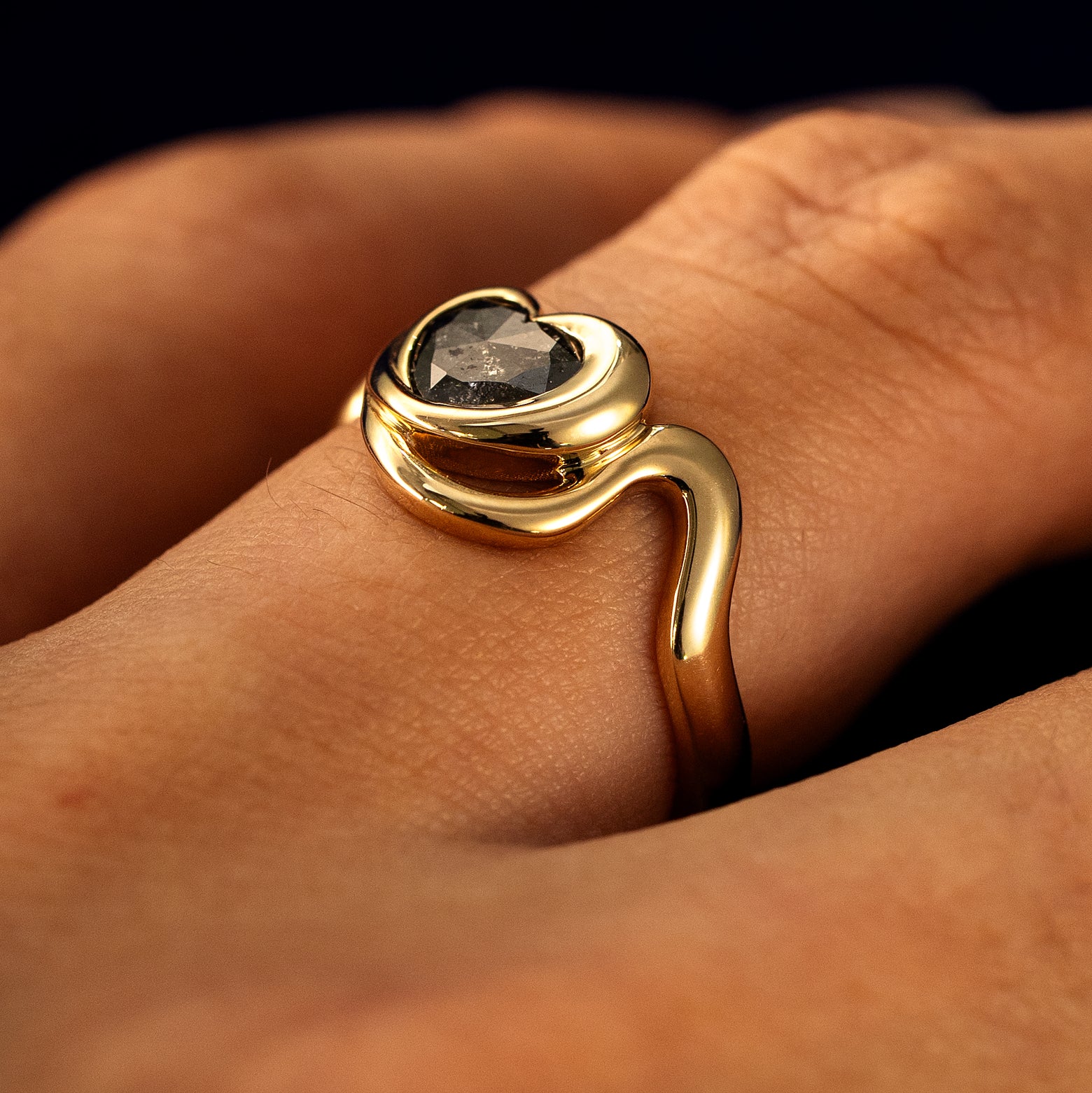 Side view of a solid 14 karat gold Heart Salt and Pepper Diamond Infinite Wave Ring on a model's finger