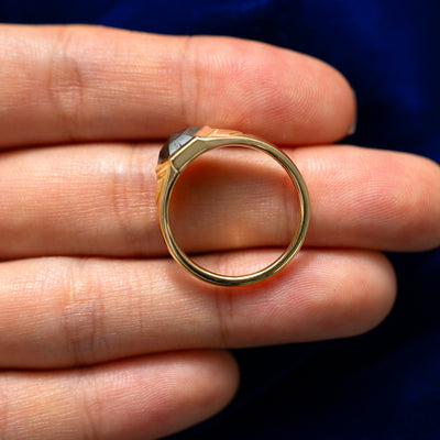 A 14 karat solid gold Transformation Ring lying on a model's fingers to show the thickness of the band
