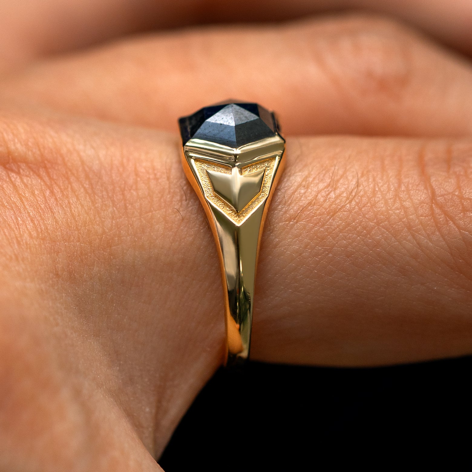 Side view of a model's finger wearing a solid 14k gold Transformation Ring to show the engravings