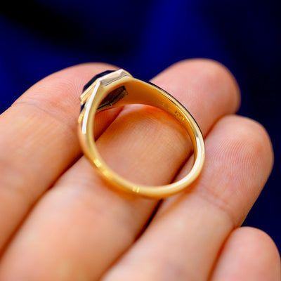 A 14 karat gold black diamond Transformation Ring lying on a model's fingers to show the stamp and underside of the stone