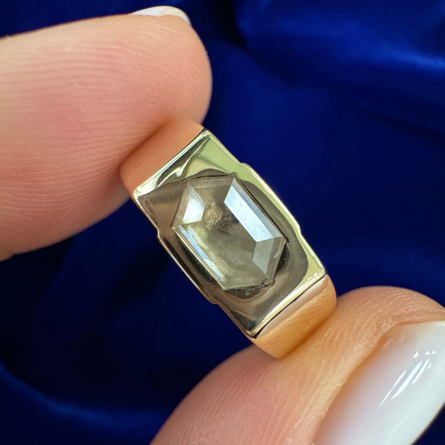 Model is holding a 14k Yellow Gold Sunken-half-bezel-set 1.19ct 8.2x5.3mm Hexagon Light Grey Salt-and-pepper Diamond on Industrial Band Custom Ring