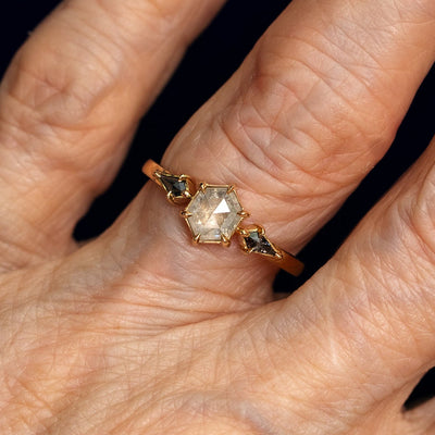 A model's hand wearing a 14k yellow gold Hexagon Salt and Pepper Diamond Black and White Ring