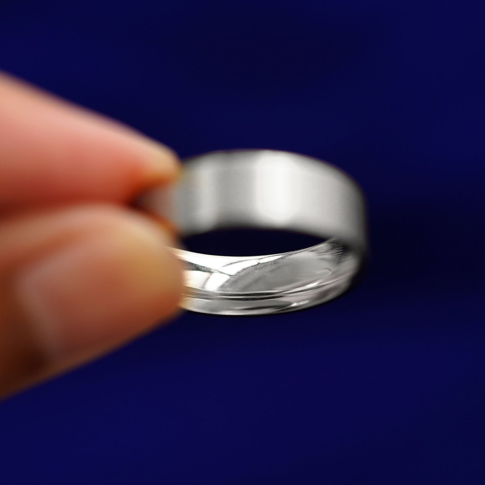 A model holding a Silver Industrial Matte Band tilted to show the inside of the band