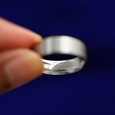 A model holding a Silver Industrial Matte Band tilted to show the inside of the band