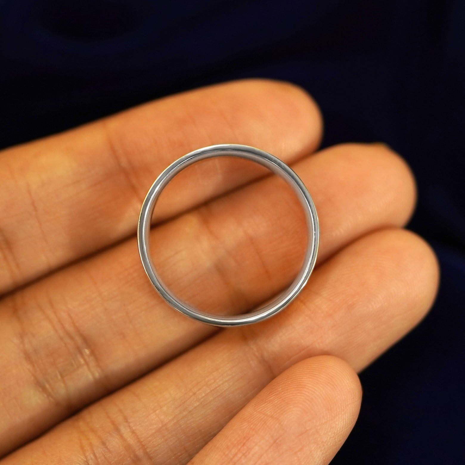A Silver Industrial Mirror Band resting on a model's fingers to show the thickness of the band