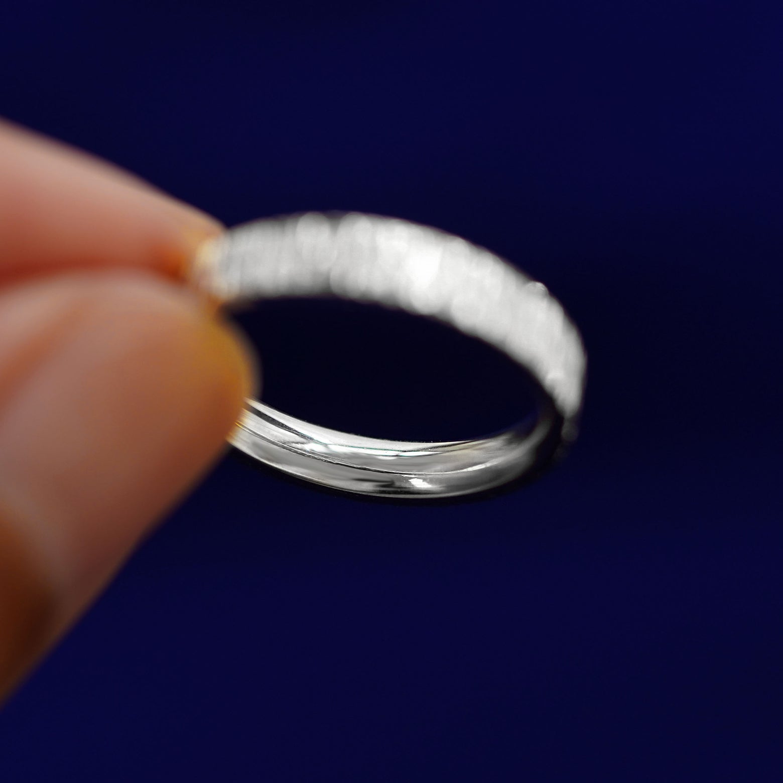 A model holding a Silver Industrial Wood Band tilted to show the inside of the band