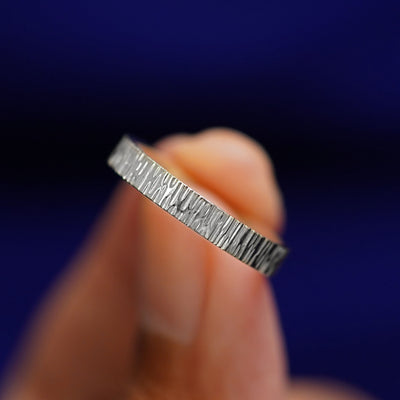 A model holding a Silver Industrial Wood Band tilted to show the details of the wood finish
