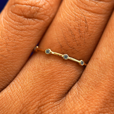 Close up view of a model's fingers wearing a 14k yellow gold Spaced Salt and Pepper Diamond Infinity Ring