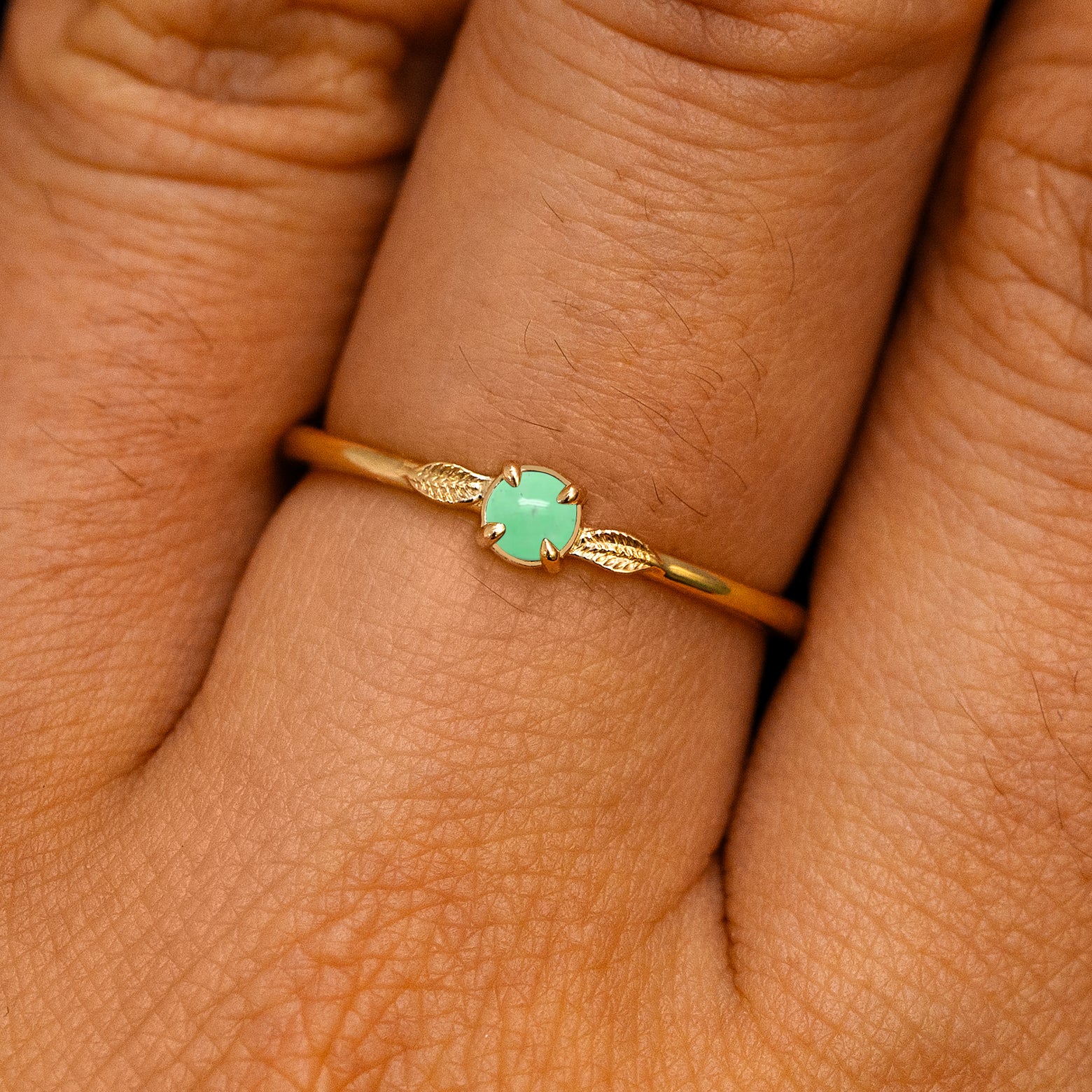 A solid 14k yellow gold Jade Gemstone Two Leaf Ring on a model's finger