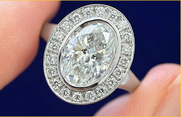 A model holding a custom oval diamond engagement ring with a diamond halo