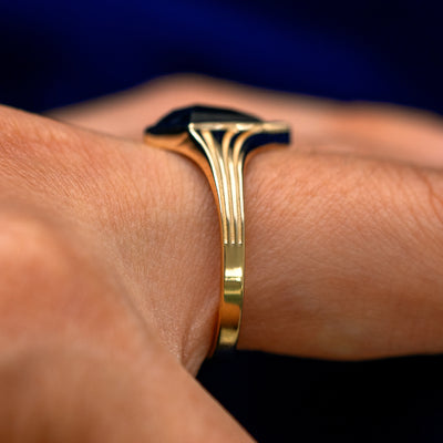 Side view of a model's finger wearing a solid 14k gold Journey Ring to show the engravings