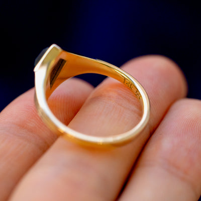 A 14 karat gold black diamond Journey Ring lying on a model's fingers to show the stamp and underside of the stone