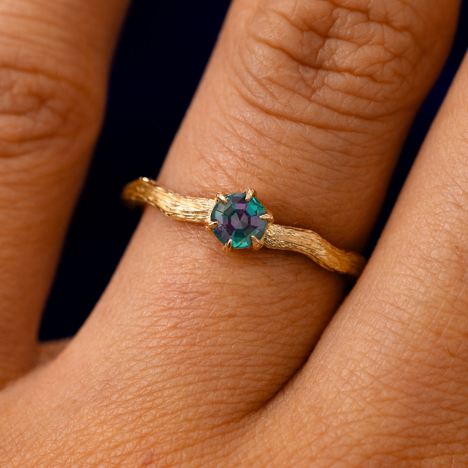 A solid 14k yellow gold Lab Alexandrite Waved Branch Ring on a model's finger