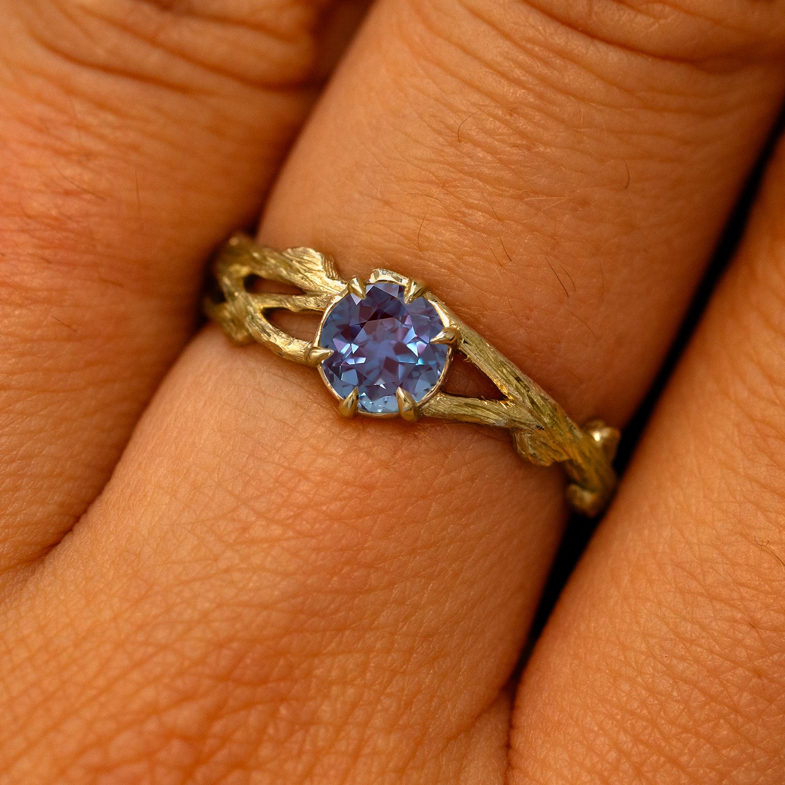 Close up view of a model's fingers wearing a 14k yellow gold Alexandrite Branches Ring