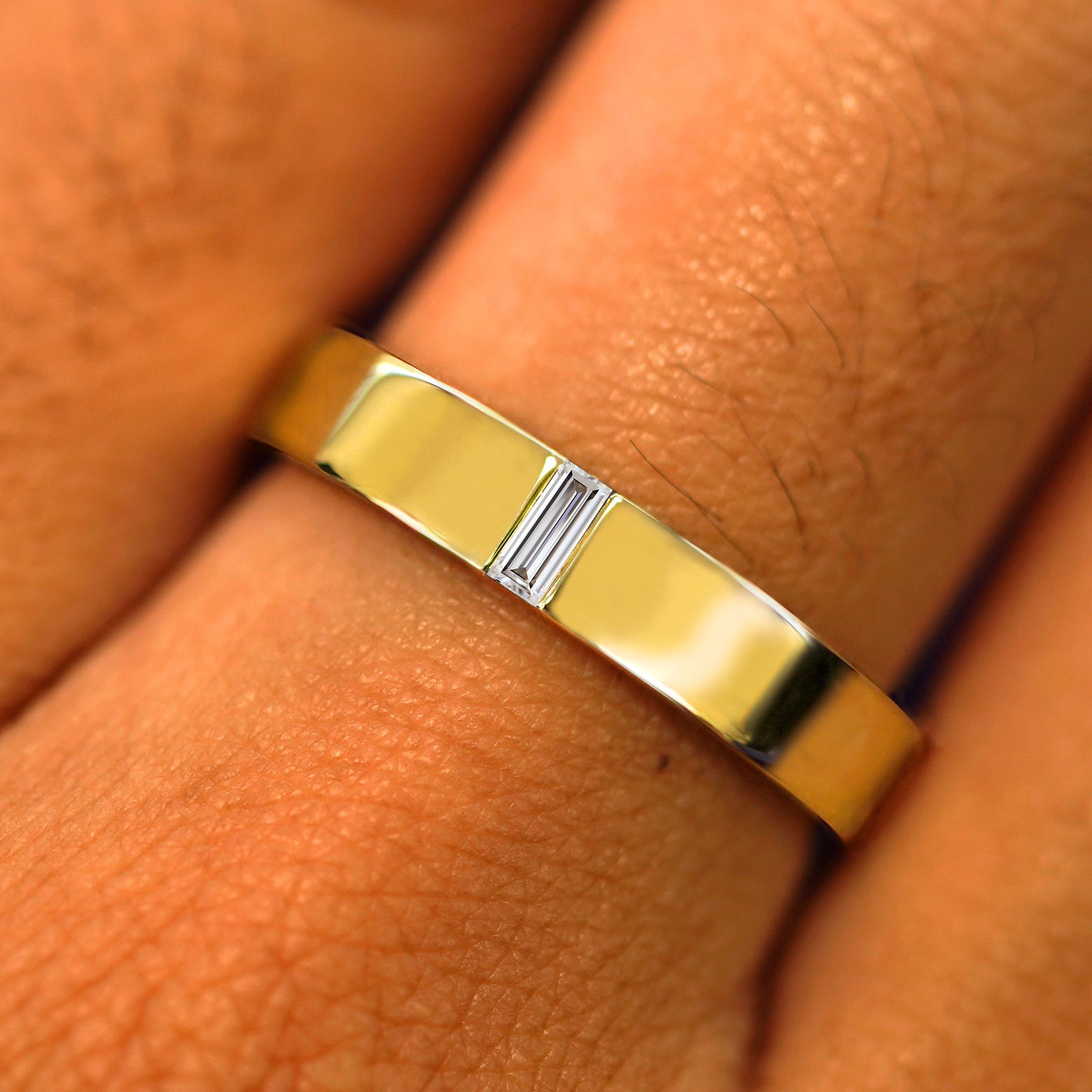 Close up view of a model's hand wearing a solid yellow gold Clear Diamond Band