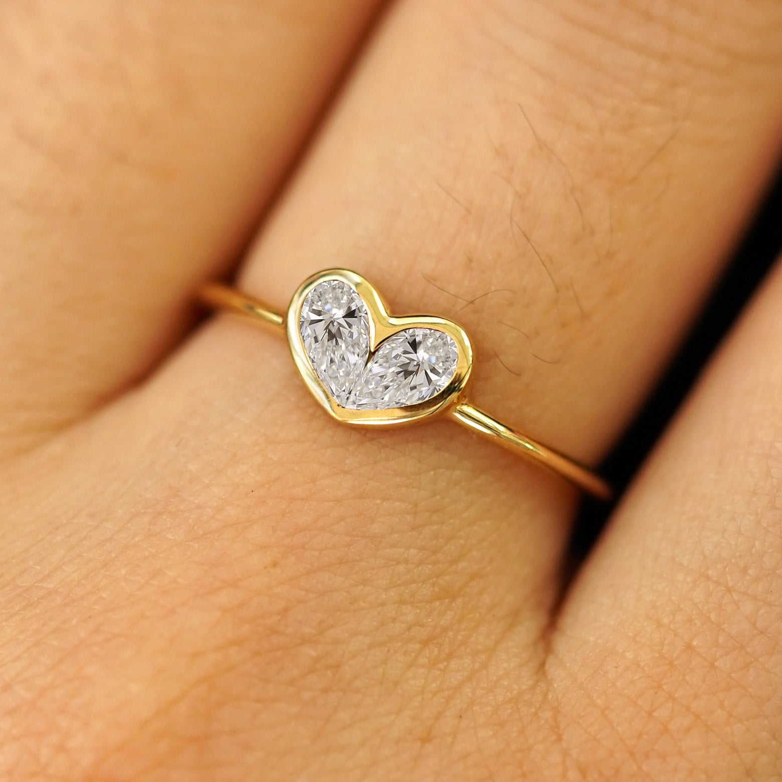 Close up view of a model's hand wearing a solid yellow gold Lab Diamond Heart Ring
