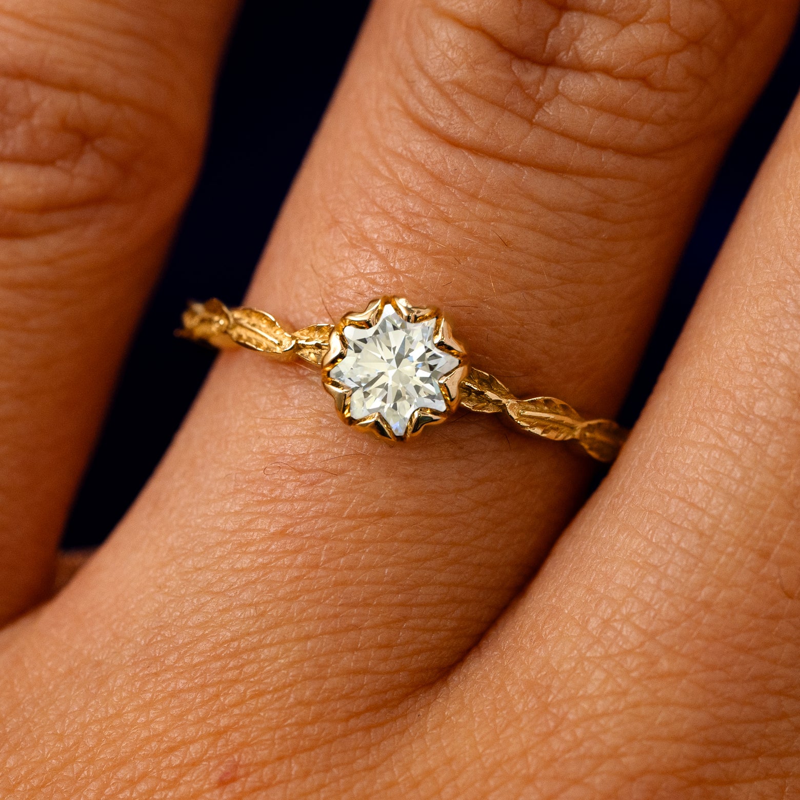 A solid 14k yellow gold clear lab diamond Leaf Ring on a model's finger