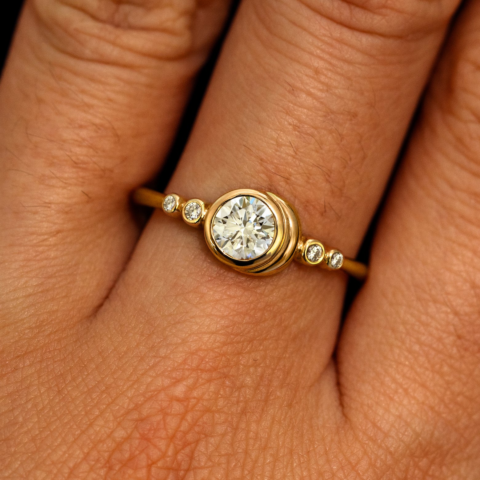 A model's hand wearing a 14k yellow gold Lab Clear Diamond Moon Ring