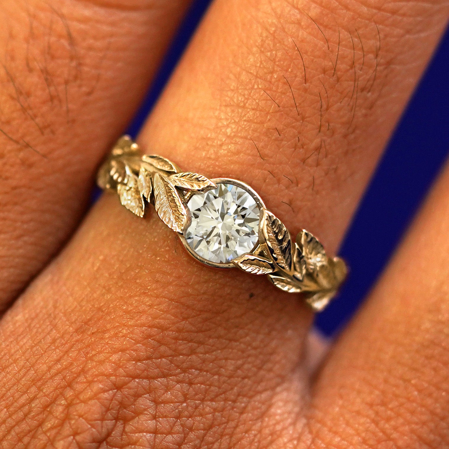 Close up view of a model's fingers wearing a 14k yellow gold Lab Clear Diamond Leaves Ring