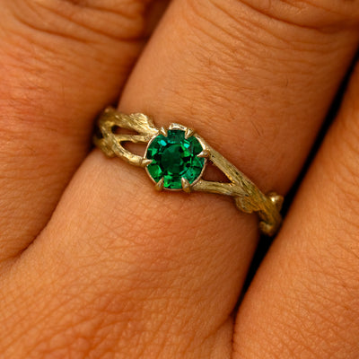 Close up view of a model's fingers wearing a 14k yellow gold Lab Emerald Branches Ring