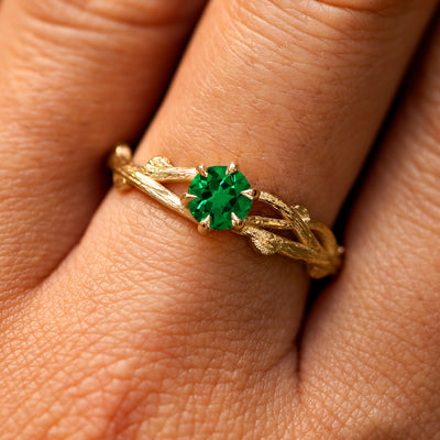Close up view of a model's fingers wearing a 14k yellow gold Lab Emerald Branches Ring