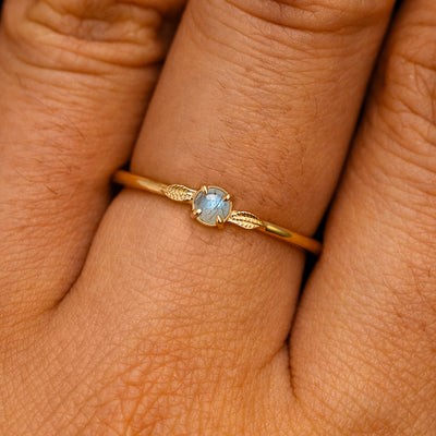 A solid 14k yellow gold Labradorite Gemstone Two Leaf Ring on a model's finger