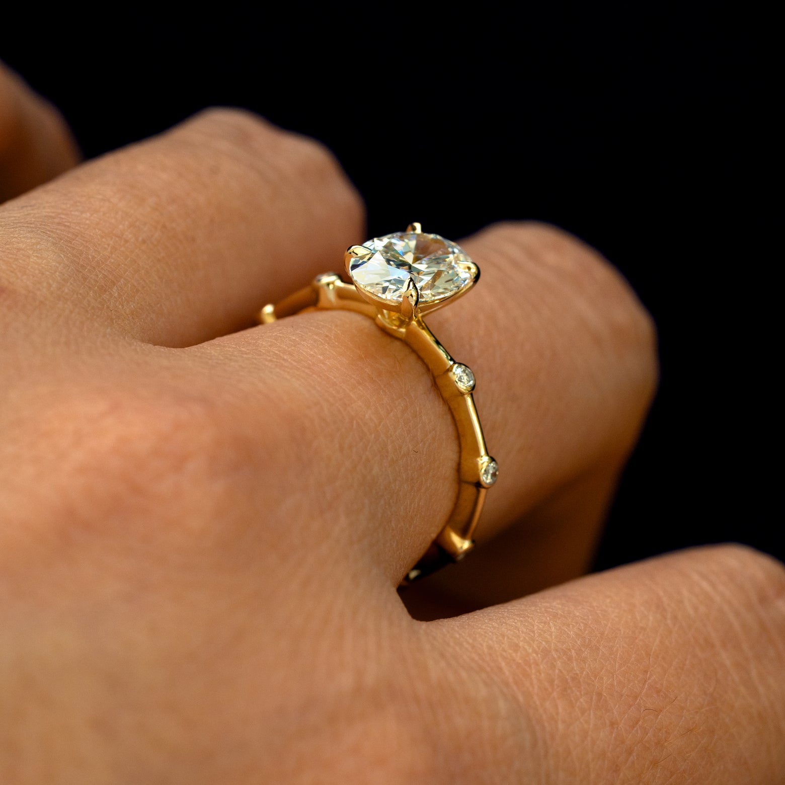 An angled view of an Oval Lab Diamond Bubble Ring on a model's finger to show the accent stones